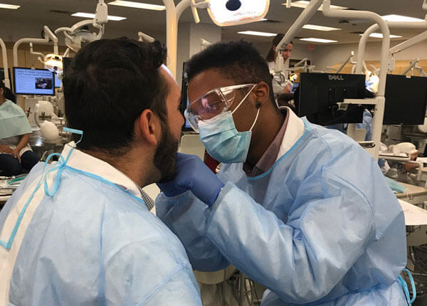 Health students in scrubs performing dental exam
