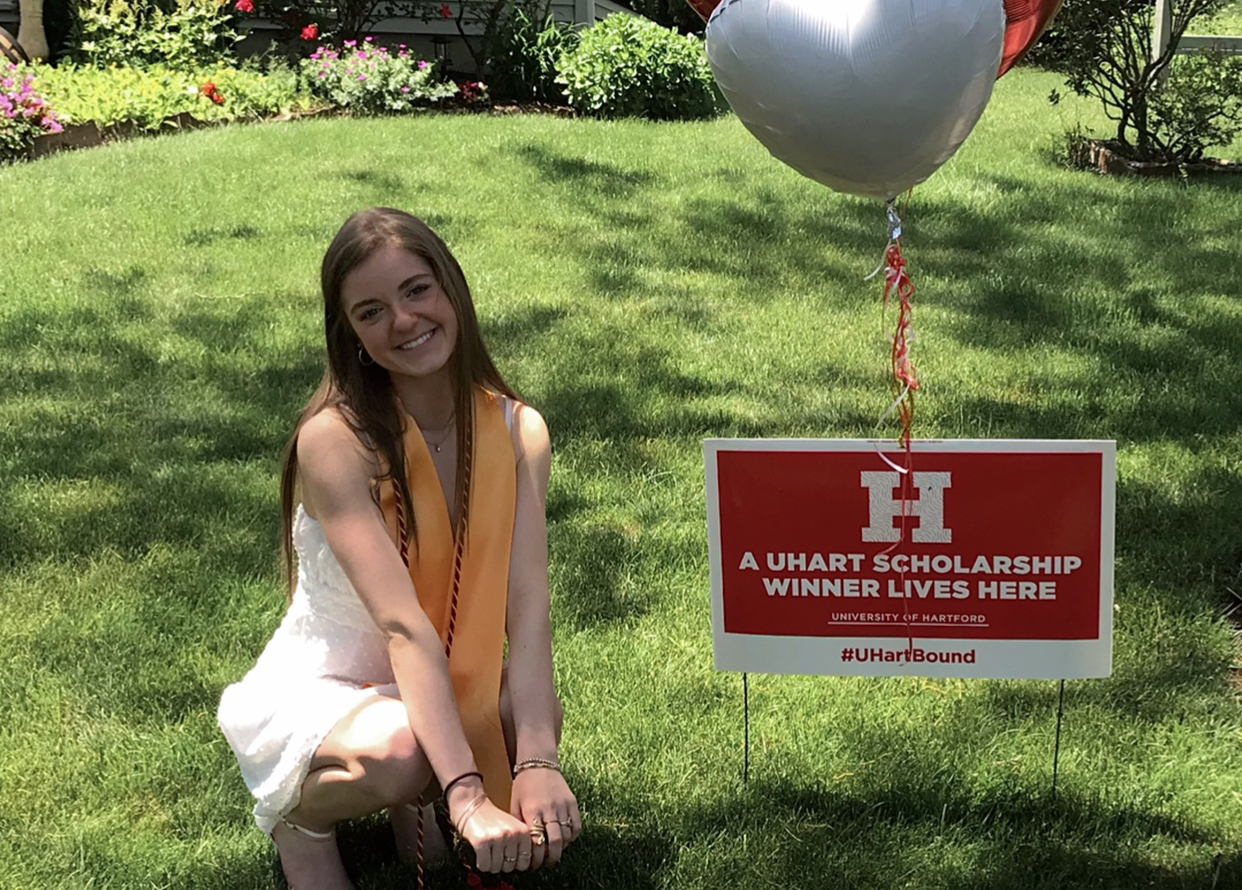 photo of Kyla next to her lawn sign announcing she's a winner of the tuition competition 