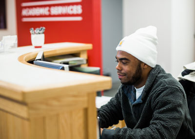 UHart student working at the Academic Services desk.