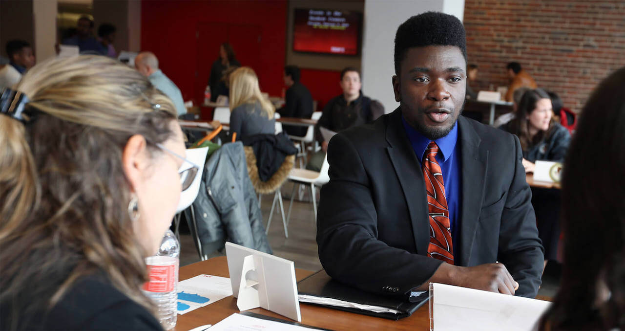 Student at a table talking with employers