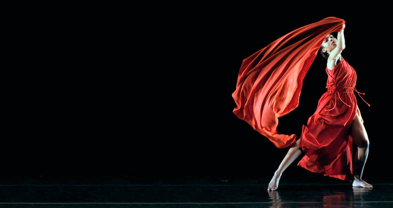 Woman on stage dancing in a dark theater