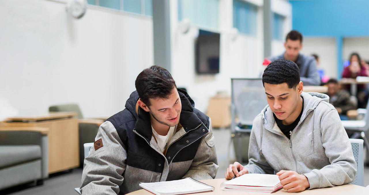 Two Student sitting at a table with note books open