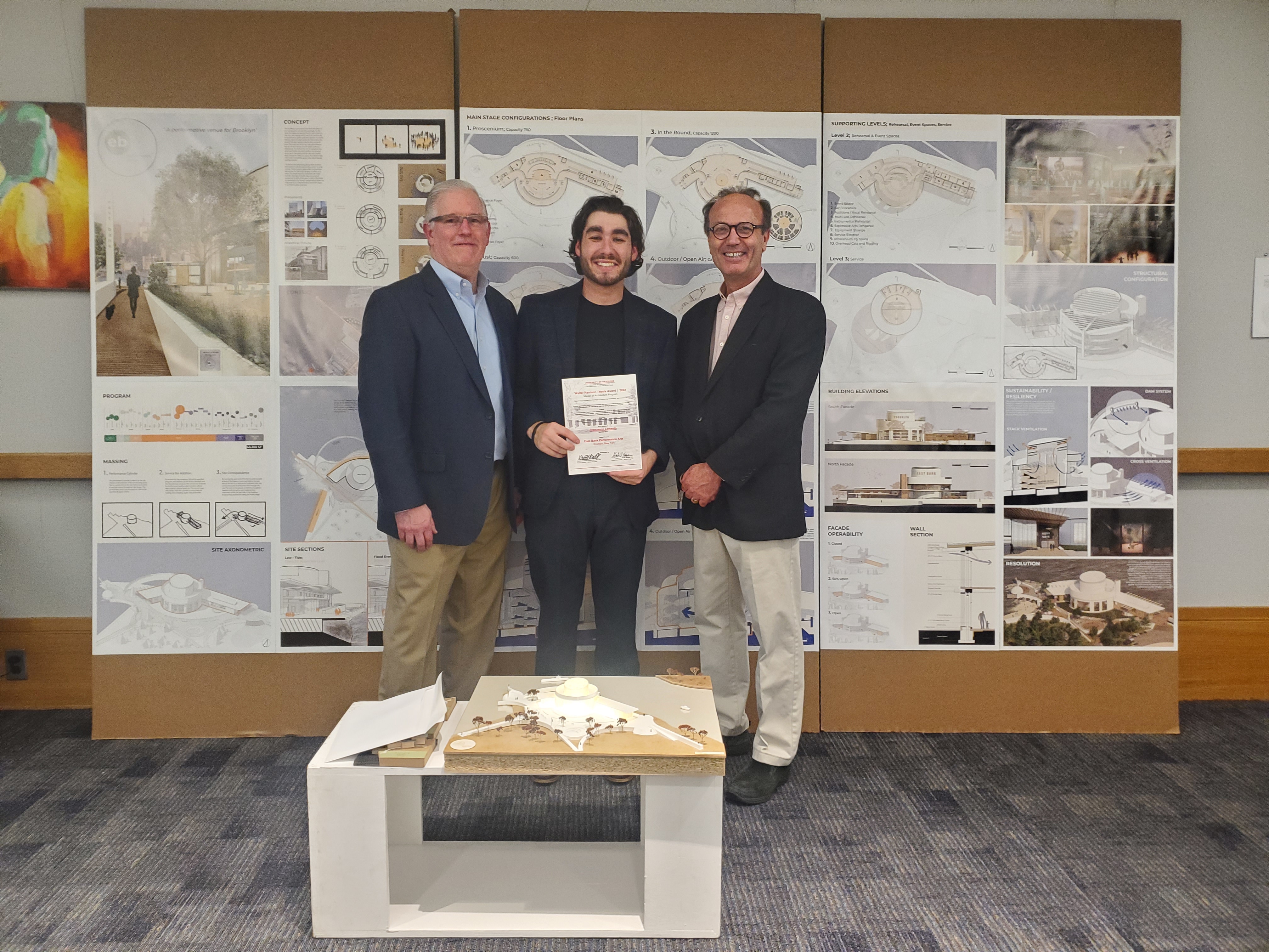 Three men together holding award with student in middle.