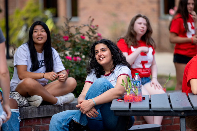 Student smiling at other student on a bench