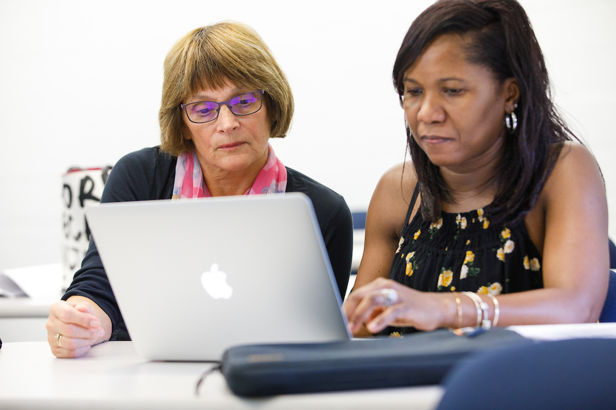 image is of a student and teacher looking at a laptop together