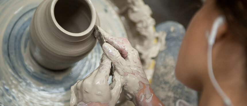 Student throwing pottery on a wheel