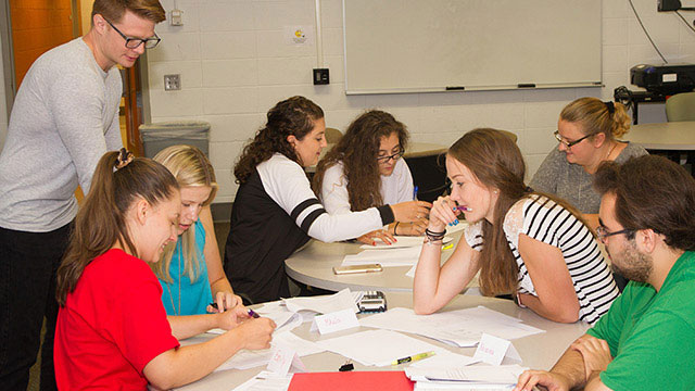 Faculty mentoring students in classroom.