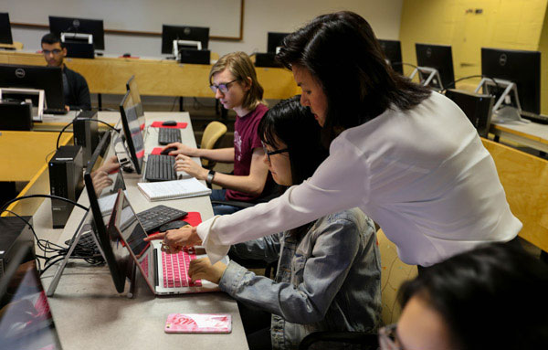 Professor helping student in computer science class. 