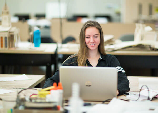 Female student smiling in front of laptop