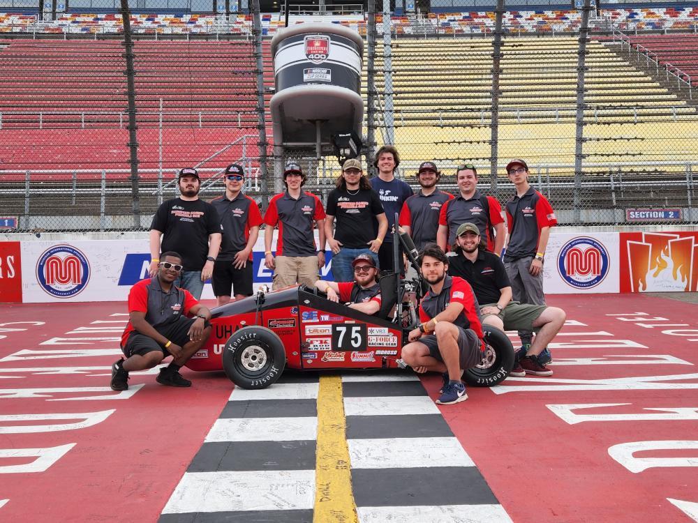 FSAE team smiling on race track with race car.