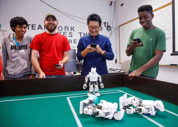 Professor with students studying robotics