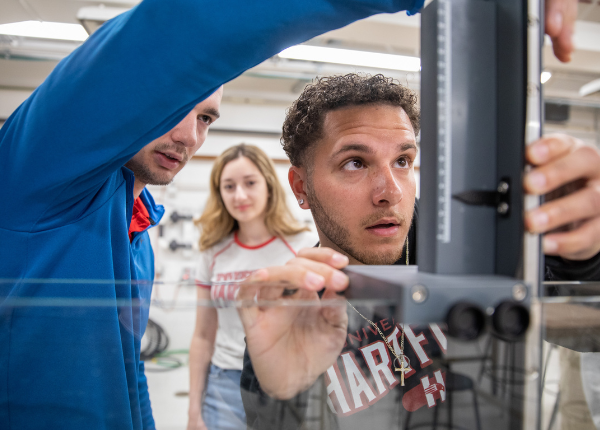 Students smiling and working on water pipe