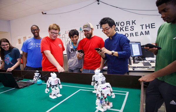 Students working in robotics lab with professor