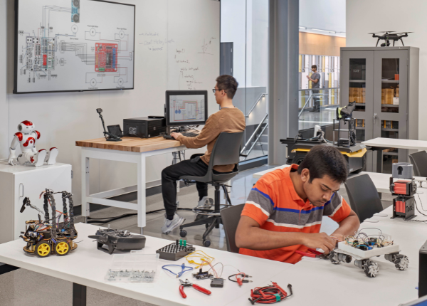 Engineering students working hands-on with robotics equipment completing group project.