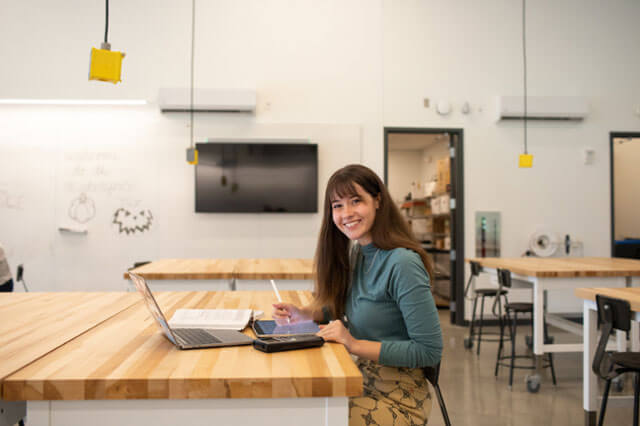 female student sitting at table and computer working on project