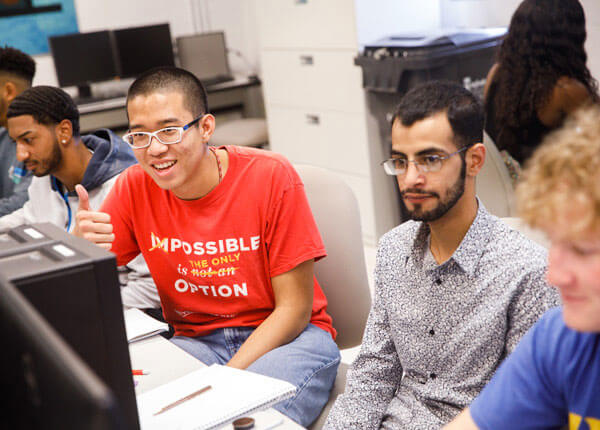 Three University of Hartford male students men looking at a computer.