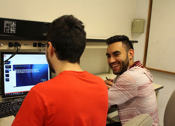 Students smiling in front of computer