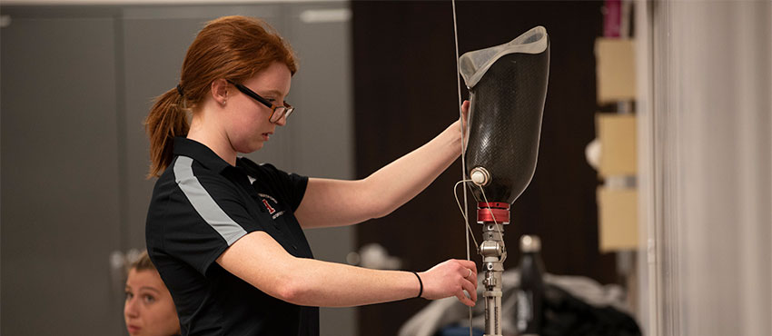 Student examining prosthetic leg