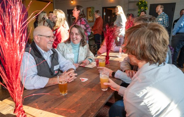 UHart alumni hanging out at and talking around a table at Alvarium brewwery.