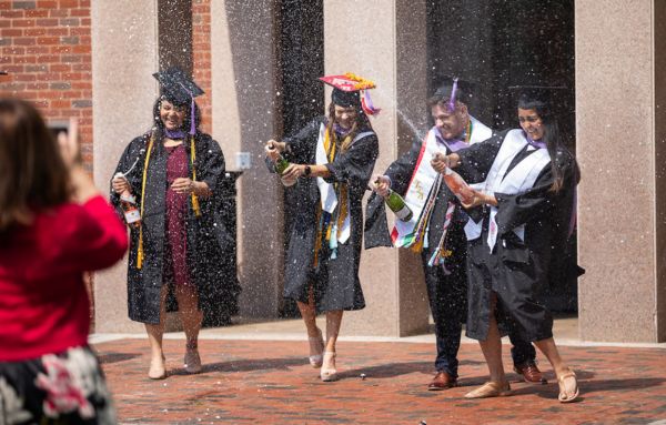Recent UHart graduates spray champagne in celebration.