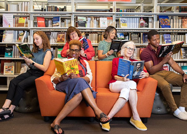 People sitting in the library reading a variety of different books