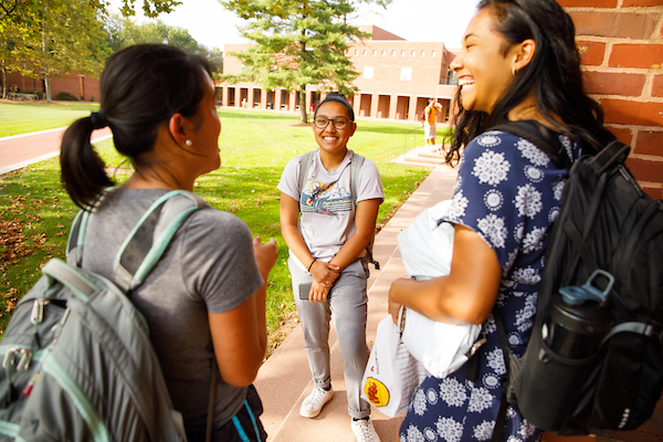 Three female students talking outside a building