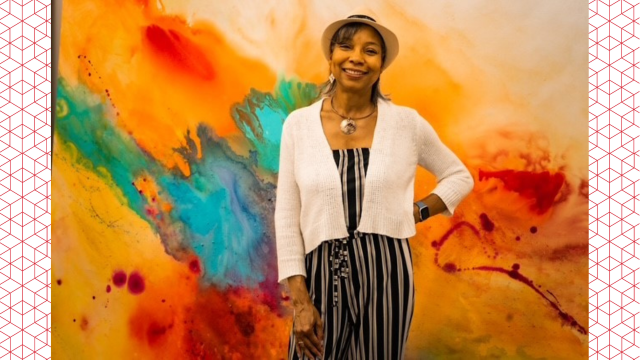Photo of Denise Gunter standing in front of a vibrant colored wall