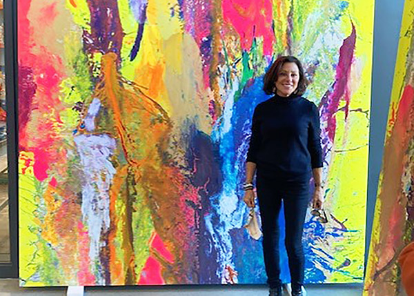 Nancy Pantirer '77 standing in front of one of the panels of Radioactive