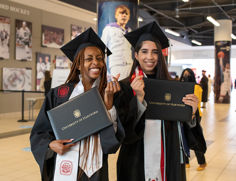two graduate students with diplomas