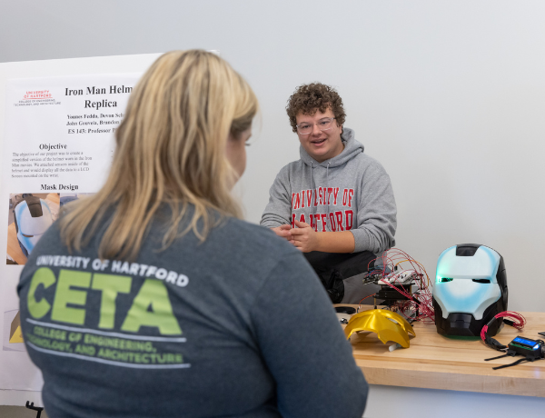 Male student presenting to female student showing iron man project